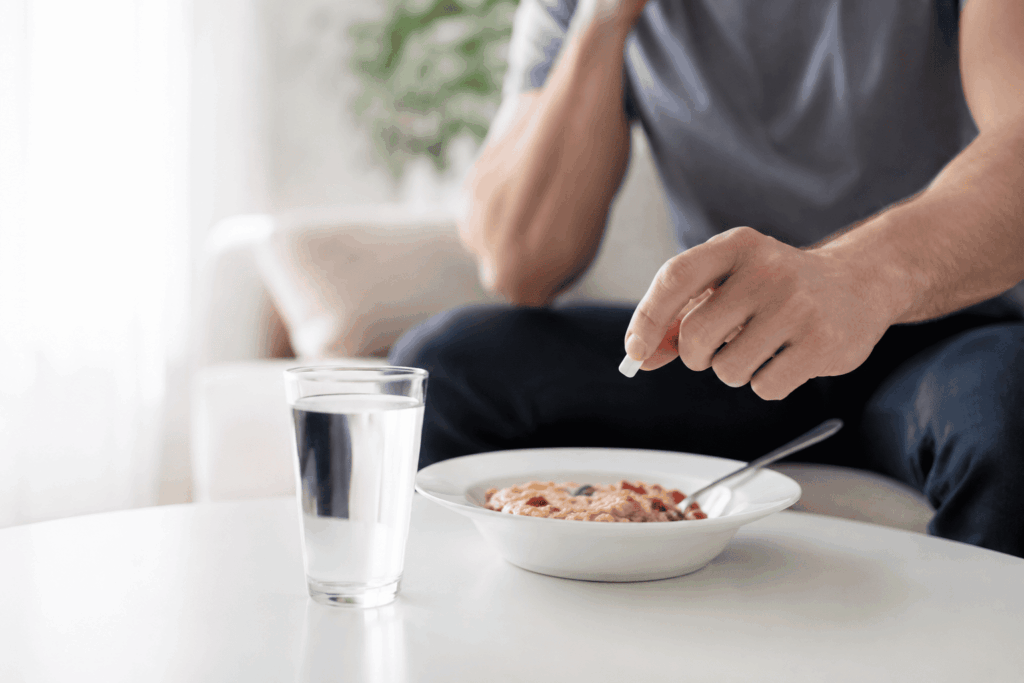 Pessoa com remédio e comida sobre a mesa