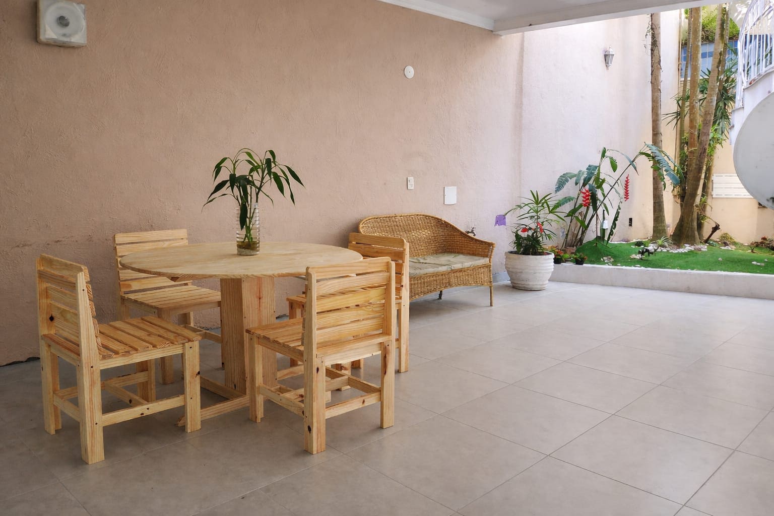 Mesa e cadeiras em área de convivência externa com plantas