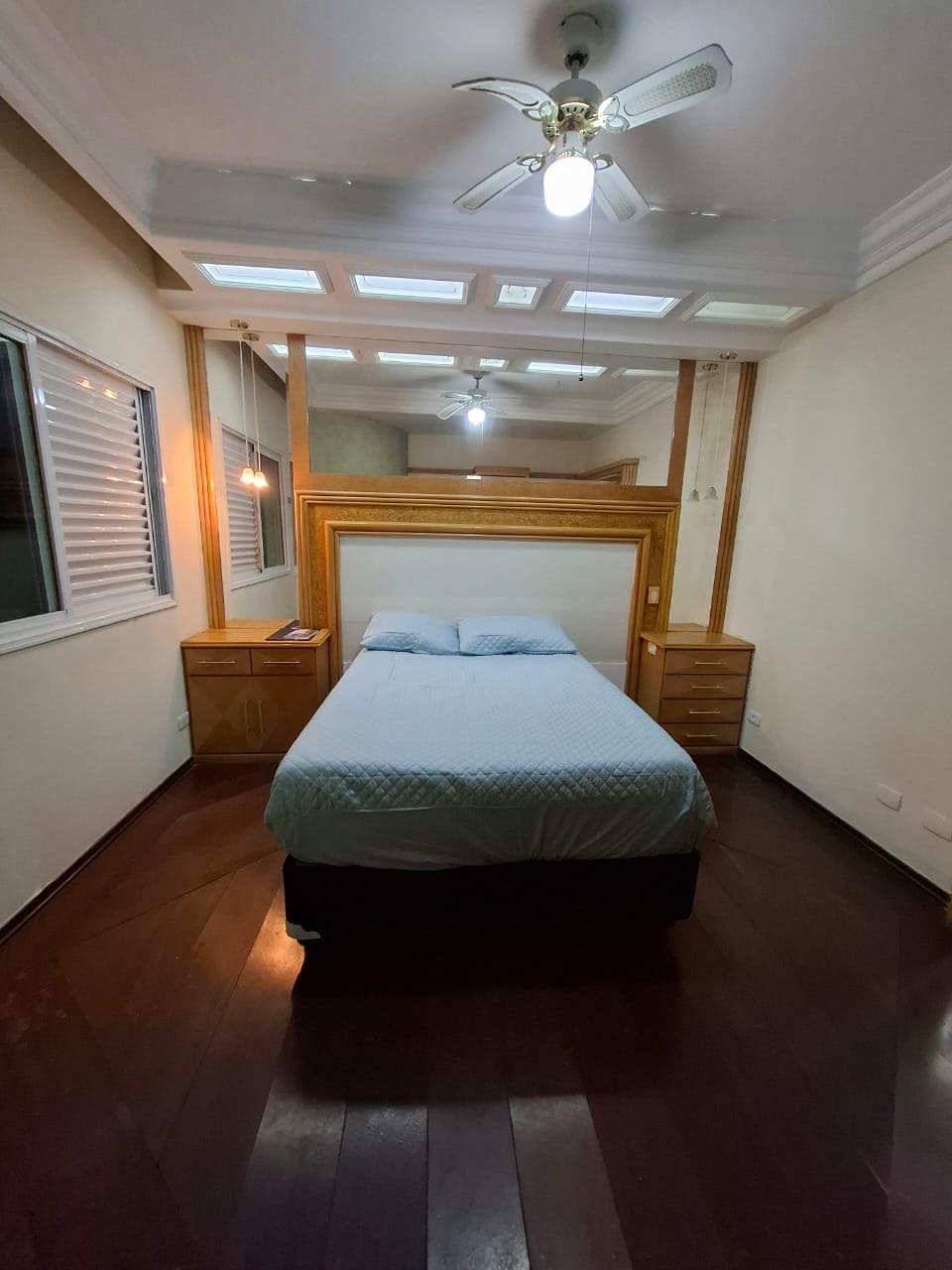 Quarto com cama, cabeceira de madeira e iluminação no teto