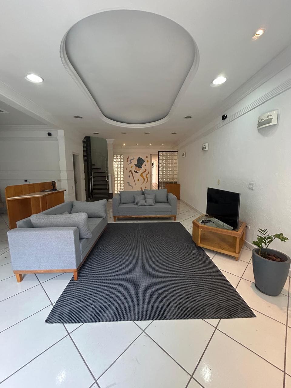 Sala de estar com sofás claros, televisão e tapete