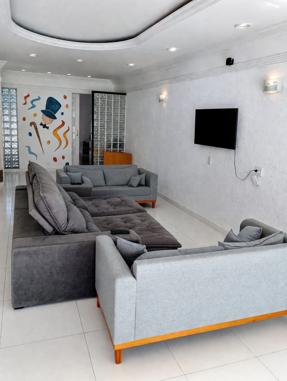 Outra vista da sala de convivência com sofás e televisão